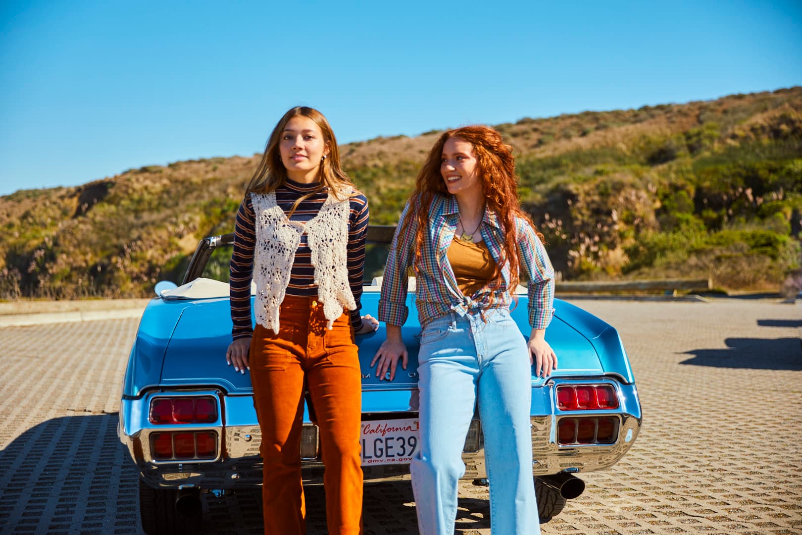 Two women modeling in front of a convertible